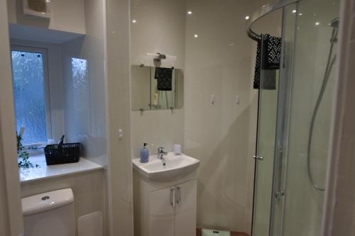 a white bathroom with a sink and a shower at CHARMING VICTORIAN APARTMENT, central location in Inverness