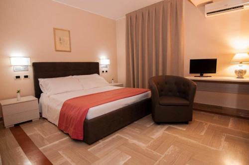 una camera d'albergo con letto e sedia di Hotel Pomara a San Michele di Ganzaria