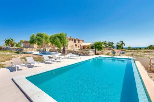 uma piscina com cadeiras e uma casa em Villa Amazing Vilafranca em Vilafranca de Bonany