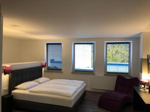 een slaapkamer met een bed, een stoel en ramen bij Hotel52 Bergheim in Bergheim