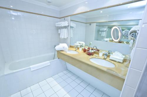 a bathroom with two sinks and a mirror and a tub at Hôtel L'Yeuse - Les Collectionneurs in Châteaubernard