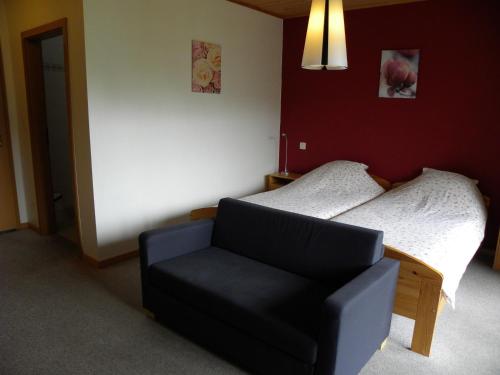a bedroom with a bed and a black chair at Hotel Restaurant Walliser Sonne in Reckingen - Gluringen