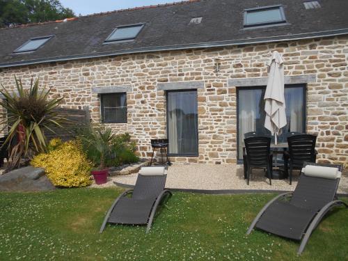 a patio with a table and chairs and an umbrella at Espace Acu-Nature in Saint-Évarzec