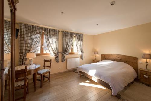 a bedroom with a bed and a desk and two windows at La Ferme de Louise in Hohengoeft