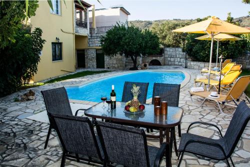 patio ze stołem i krzesłami przy basenie w obiekcie Villa Dimitris w mieście Kalamitsi Amygdali