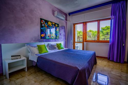 a bedroom with a bed with purple walls and a window at GH Campoverde Village in San Cataldo