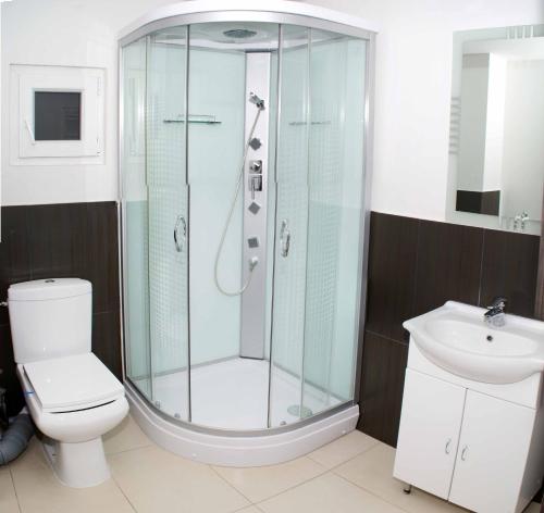 uma casa de banho com um chuveiro, um WC e um lavatório. em Hotel Otopeni em Otopeni