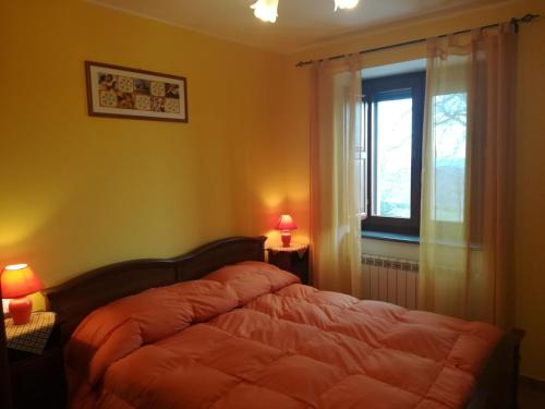 a bedroom with a bed with a window and two lamps at guado cannavina in Capracotta
