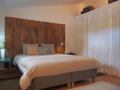 a bedroom with a large bed with a wooden headboard at Monte dos Freixos Country House in São Lourenço de Mamporcão