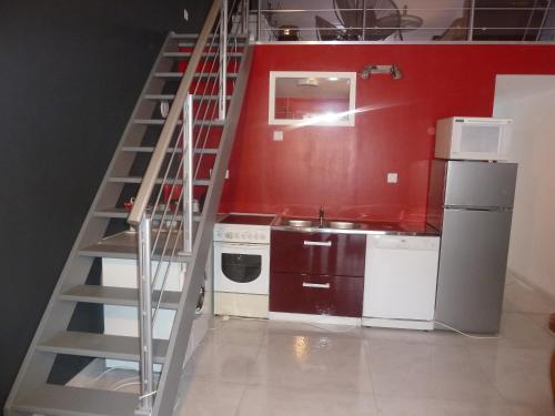 a kitchen with a staircase next to a red wall at Gite Au Cheval D'or in La Meilleraie-Tillay