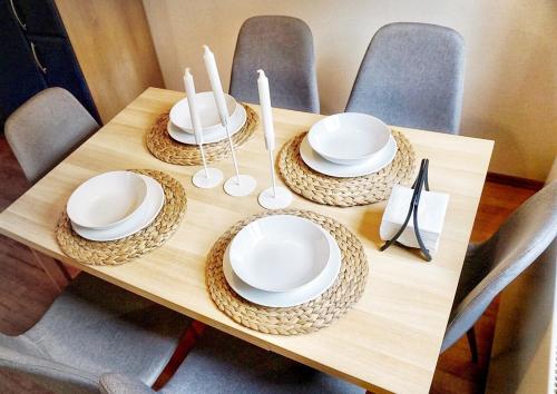 ein Holztisch mit weißen Tellern und Servietten darauf in der Unterkunft Central Suites - Špindlerův mlýn in Špindlerův Mlýn