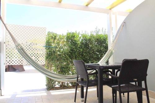 a hammock on a patio with two chairs and a table at Quinta Da Rosa Linda in Monte Gordo