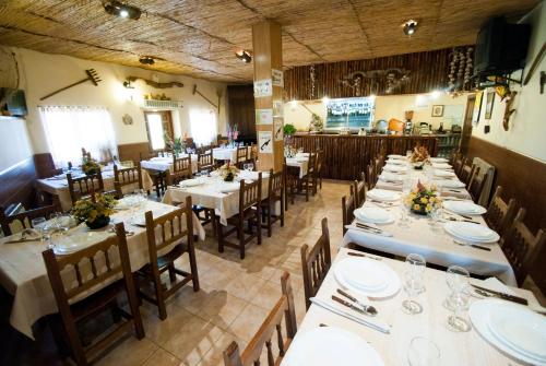 un comedor con mesas largas y sillas con platos y vasos en Los Arribes, en Moralina