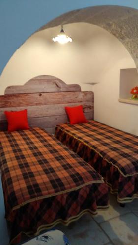 a bedroom with two beds with red pillows at Trulli in Valle D'Itria in Cisternino