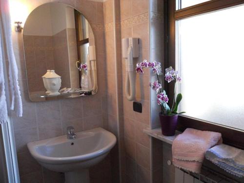 baño con lavabo, espejo y flores en La Cascina Di Villa Due, en Narzole