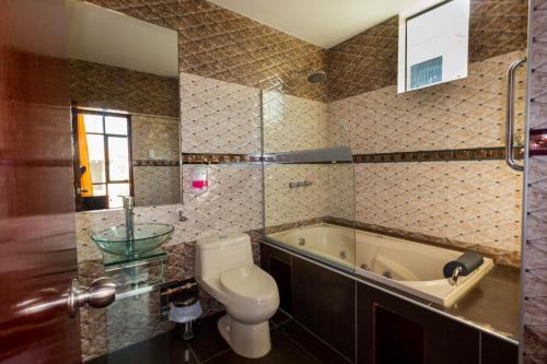 a bathroom with a toilet and a bath tub at Hotel Suite Naylamp Zyon in Jaén