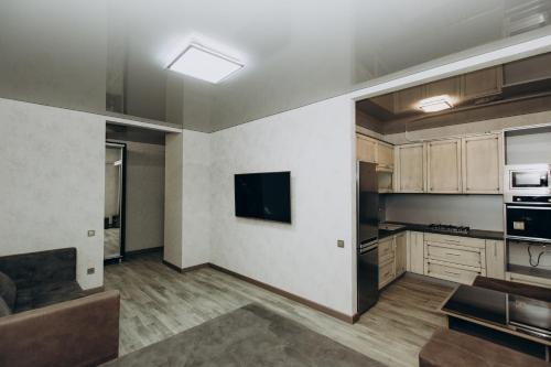 an empty kitchen with a couch and a television at Greatest Luxury Apartment in Sumy