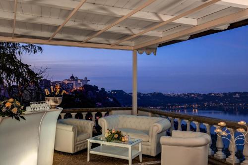 a patio with white furniture and a view of the water at Hotel Castel Vecchio in Castel Gandolfo