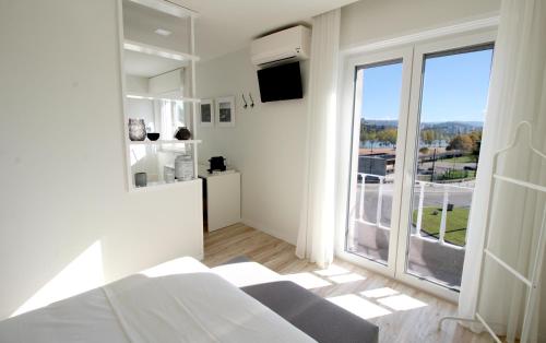 een witte kamer met een bed en een groot raam bij JR Studios & Suites I Rius I in Coimbra