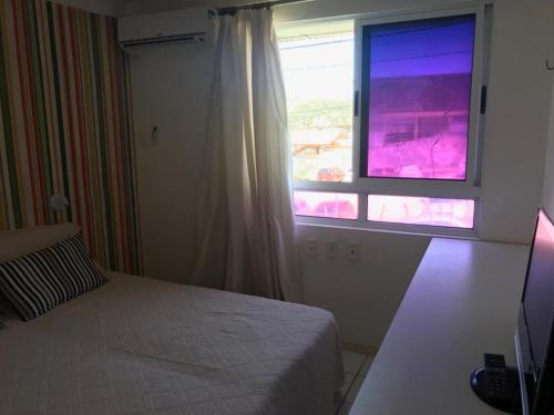 a bedroom with a bed and a window at Apartamento Ponta Negra in Natal