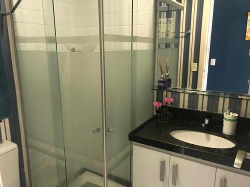 a bathroom with a glass shower and a sink at Apartamento Ponta Negra in Natal