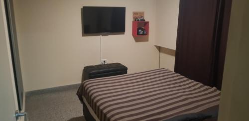 1 dormitorio con 1 cama y TV en la pared en 76 Arruabarrena, en Villa Carlos Paz