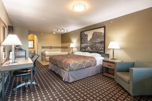 a hotel room with a bed and a desk at Super 8 Dallas East Near Fair Park Downtown in Dallas