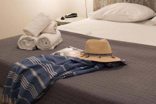 a bed with towels and a hat on it at Eva Mare Hotel & Suites - Adults only in Agia Pelagia