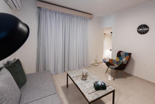 a living room with a couch and a table and a chair at Eva Mare Hotel & Suites - Adults only in Agia Pelagia