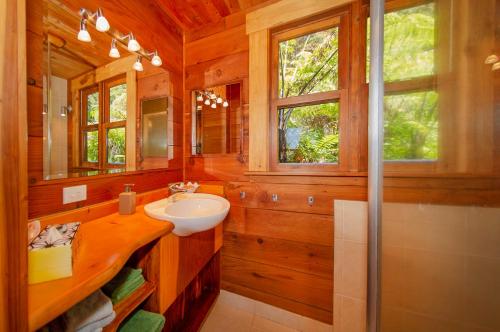 y baño con lavabo, espejo y ducha. en Kuaotunu Chalets en Kuaotunu