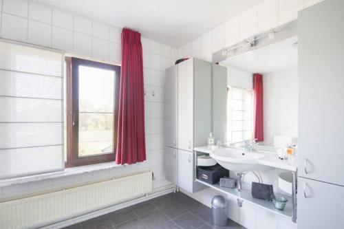 a white bathroom with a sink and a window at Guesthouse De Steenberg tweepersoonskamer met grote badkamer, kitchenette en tuinzicht op de eerste verdieping in Geel