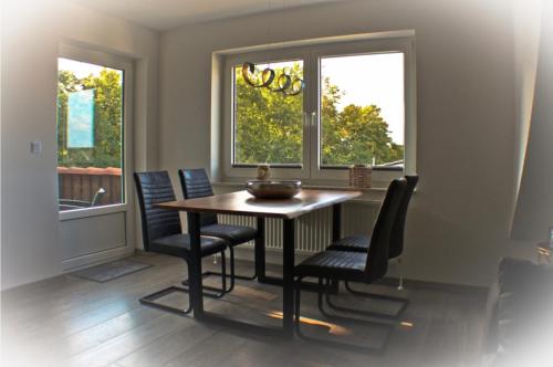 a dining room with a table and chairs and two windows at Pura Vida Fehmarn in Fehmarn