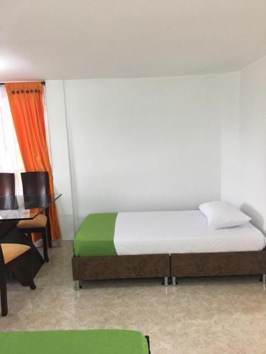 a bedroom with a bed and a desk and a chair at Alojamiento Campestre Hawaii in Montenegro