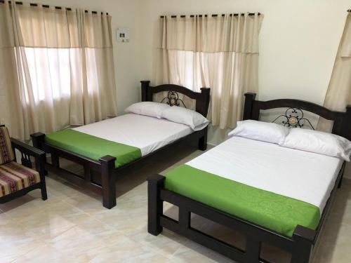 two beds in a room with a couch and a chair at Alojamiento Campestre Hawaii in Montenegro