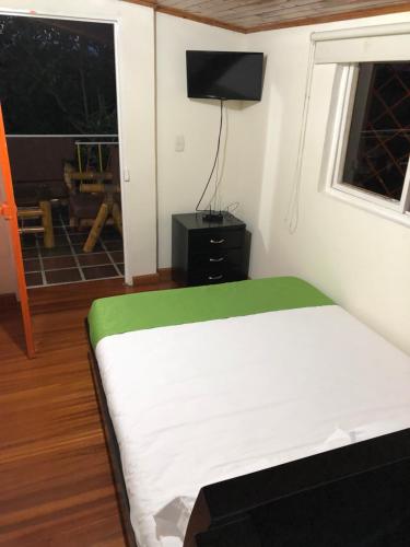 a bedroom with a bed and a window and a television at Alojamiento Campestre Hawaii in Montenegro