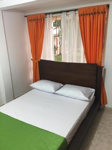 a bedroom with a bed with an orange curtain at Alojamiento Campestre Hawaii in Montenegro
