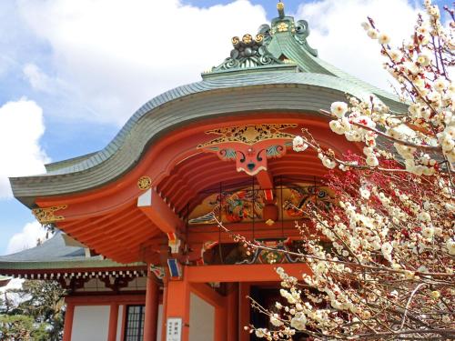 an orange building with a green roof and a tree at Hotel Wing International Kobe - Shinnagata Ekimae in Kobe