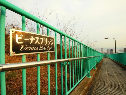 a sign on the side of a green fence at Hotel Wing International Kobe - Shinnagata Ekimae in Kobe