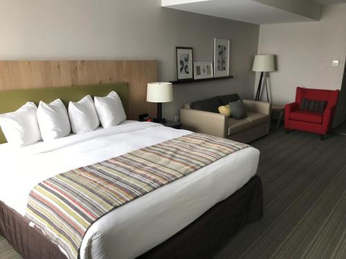 a hotel room with a large bed and a red chair at Country Inn & Suites by Radisson, Belleville, ON in Belleville