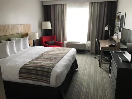 a hotel room with a large bed and a desk at Country Inn & Suites by Radisson, Belleville, ON in Belleville