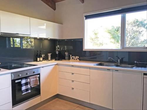 a kitchen with white cabinets and a sink and a window at Prom Beach House in Sandy Point