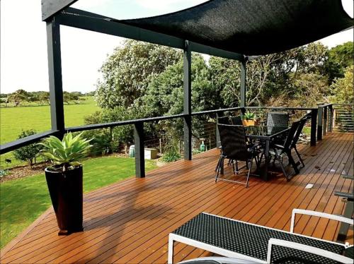 a wooden deck with a table and chairs on it at Prom Beach House in Sandy Point