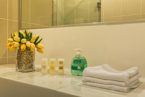 a bathroom counter with a vase of flowers and a mirror at Luxfort 118 Service Suites in George Town