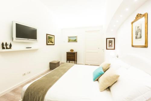 a white bedroom with a large bed and a flat screen tv at Residenza San Luca Praiano in Praiano