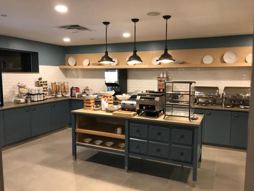 a kitchen with blue cabinets and a counter with food on it at Country Inn & Suites by Radisson, Belleville, ON in Belleville