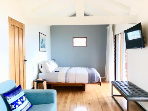 a bedroom with a bed and a couch and a tv at Piha Tiny House in Piha