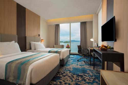 a hotel room with two beds and a desk and a window at Swiss-Belhotel Papua in Jayapura