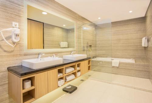 查亞普拉的住宿－瑞士貝爾帕普亞酒店，浴室设有2个水槽、镜子和浴缸。