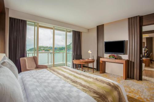 a hotel room with a bed and a large window at Swiss-Belhotel Papua in Jayapura