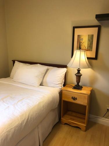 a bedroom with a bed and a table with a lamp at Cozy Bedrooms Guest House in Vancouver